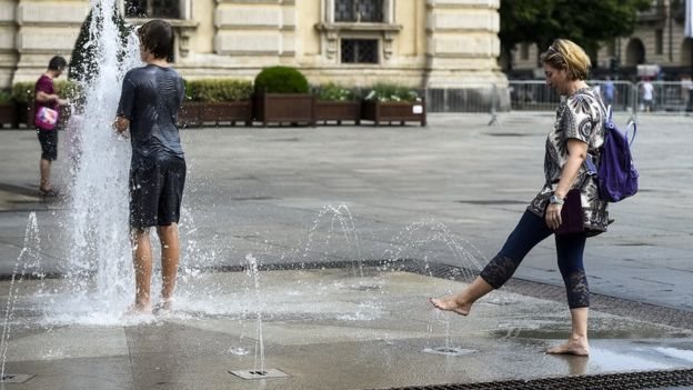 Personas refrescándose en fuentes de agua durante una ola de calor