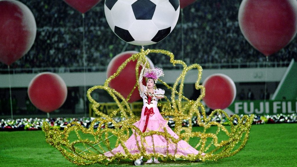 A performer dances beneath a balloon designed in the pattern of a soccer ball during the opening ceremony on November 16, 1991, in Guangzhou