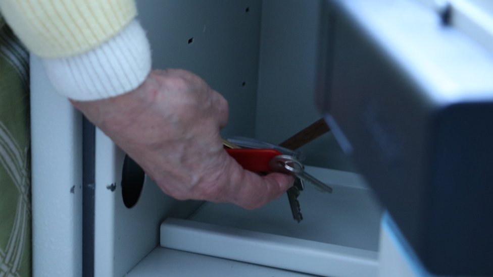 Jackie tomó medidas prácticas como colocar sus llaves en una caja de seguridad durante las noches. La misma no abría hasta las 6 de la mañana. Jackie poniendo sus llaves en una caja de seguridad.