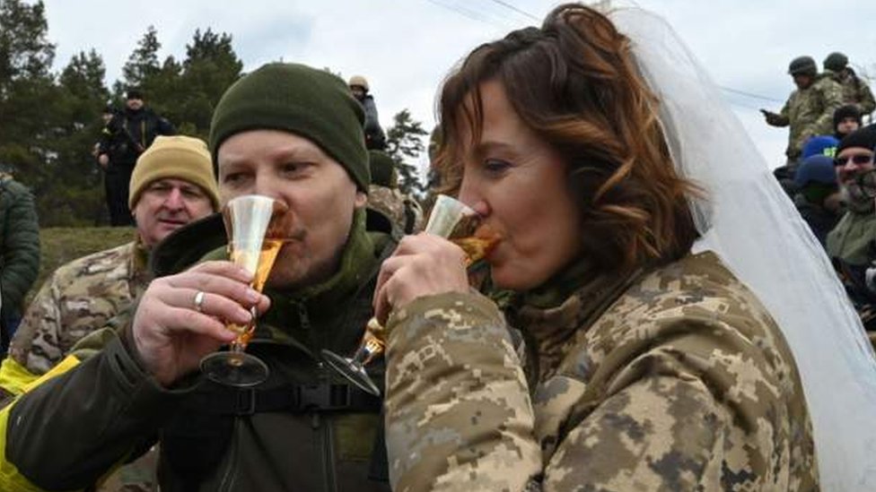 Sorridentes, Valery e Lesya compartilham uma bebida na celebração