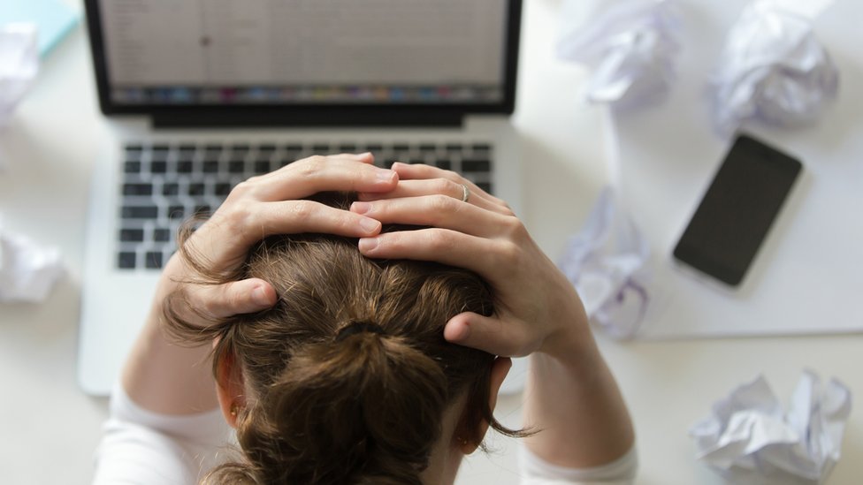 mujer usando laptop con manos en la cabeza