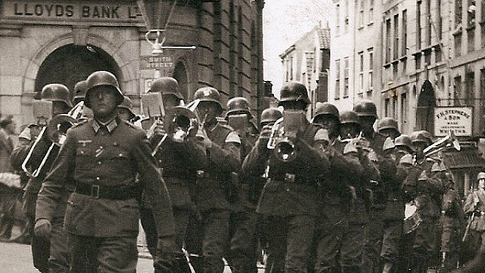 Немецкая группа марширует по улице Сент-Питер-Порт-Хай-стрит на Гернси