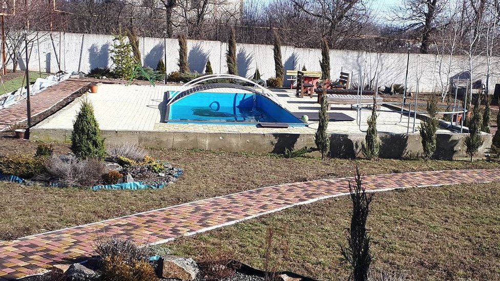 The garden of Marina's home, with a neatly laid path, swimming pool, lawn and plants.