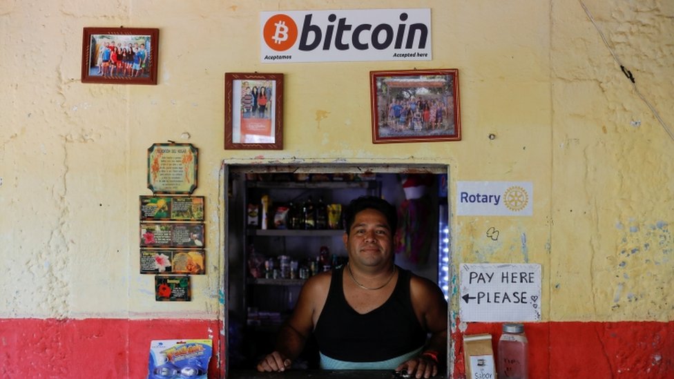 Un hombre en su tienda que acepta bitcoins como pago.