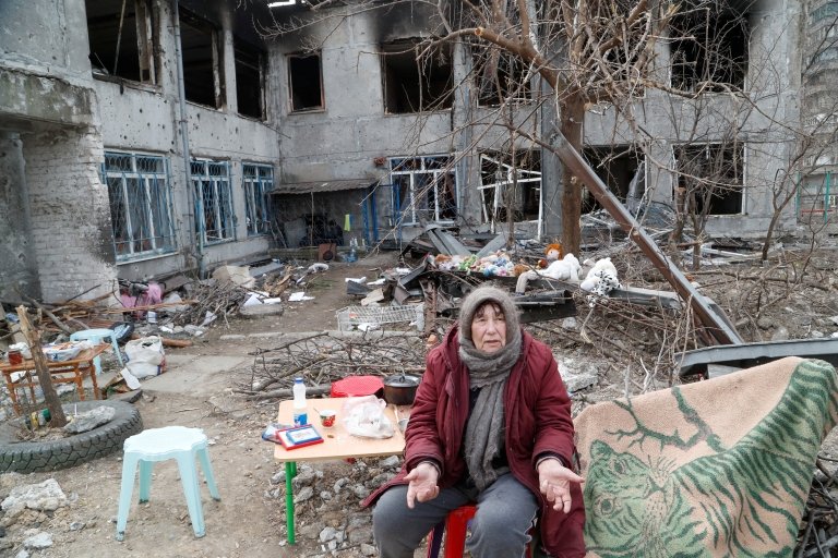 Una anciana frente a las ruinas de una escuela en Mariúpol