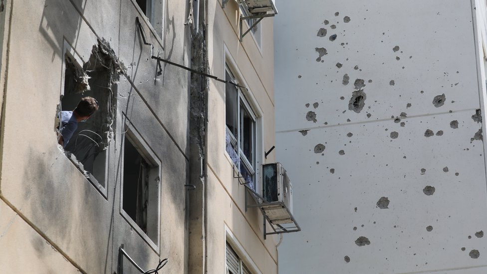 A man looks at the damage caused by a Palestinian rocket that hit a block of flats in the southern Israeli city of Ashkelon (11 May 2021)