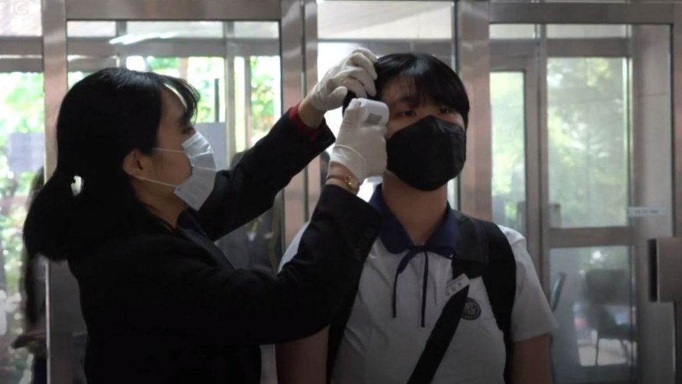 Una funcionaria toma la temperatura de un estudiante en una escuela de Seúl, Corea del Sur