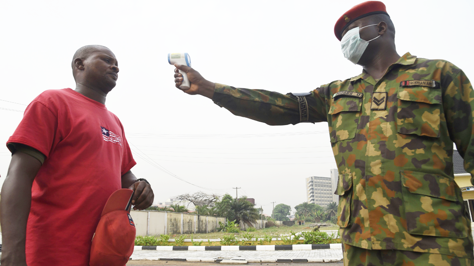 Солдат направляет термометр на мужчину в больнице нигерийской армии в Лагосе, Нигерия - пятница, 28 февраля 2020 года