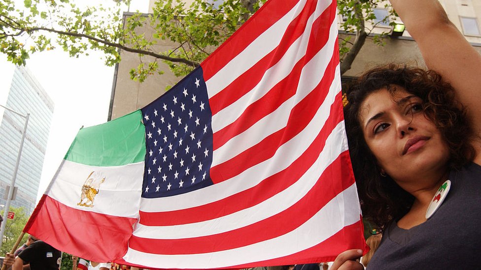 Mujer sosteniendo banderas de Irán y Estados Unidos.