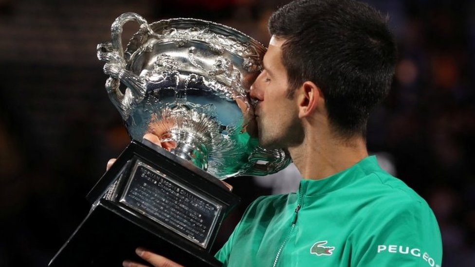 Novak Djokovic kisses a trophy he was awarded for winning last year's Australian Open title
