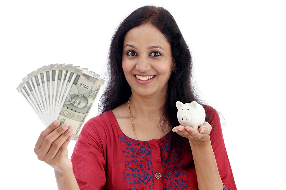 Una mujer india sostiene dinero en una mano y un chanchito de monedas en la nota