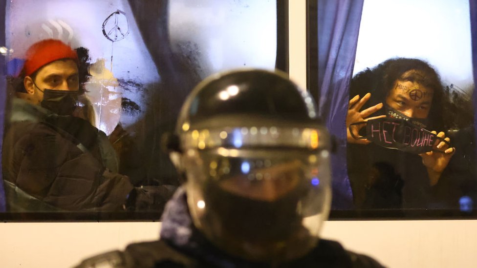 Un oficial de la policía antidisturbios y manifestantes detenidos durante una protesta contra la guerra en el centro de San Petersburgo.