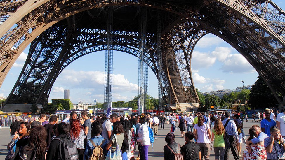 Personas caminando en la base de la Torre Eiffel