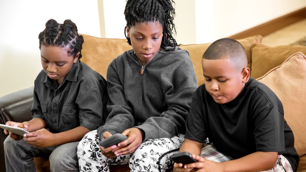 tres niños usando celulares