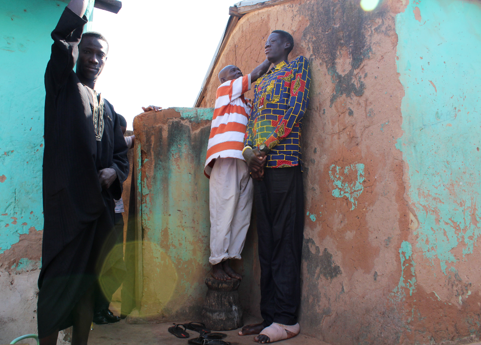 Un vecino se paró en un taburete para marcar la pared al medir Awuche.