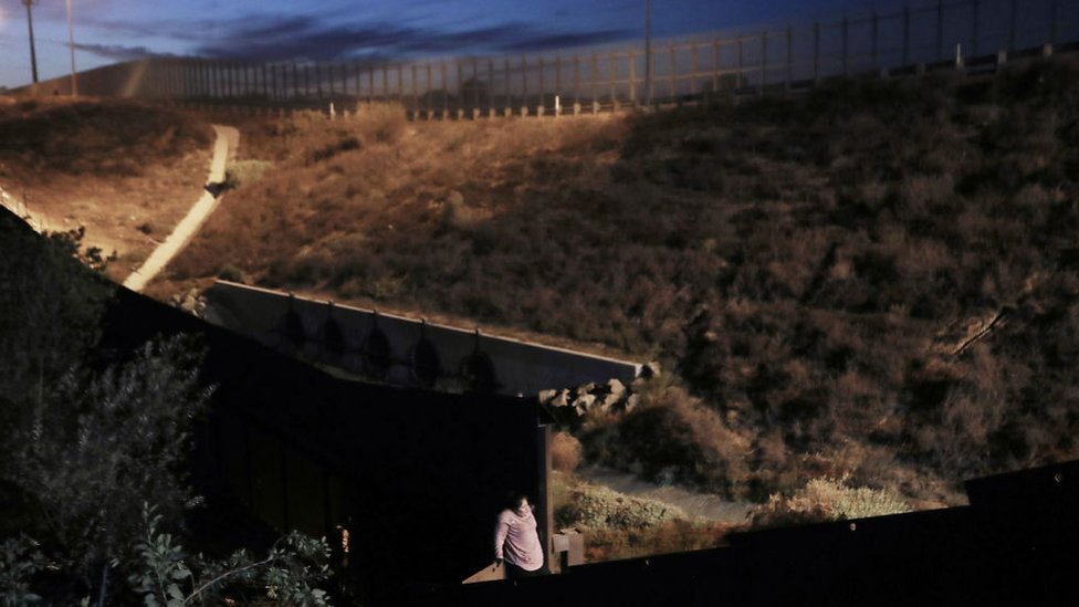 Una mujer cruza el muro fronterizo entre México y Estados Unidos en diciembre de 2018.