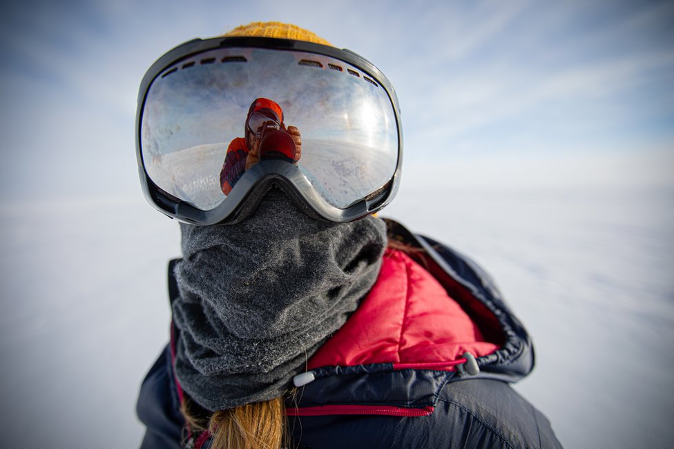 Человек в больших очках - в ледяном антарктическом пейзаже ... а также теплое пальто и шарф