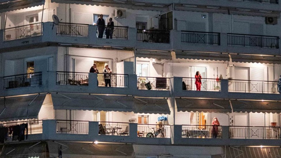 Un edificio de apartamentos con personas en cuarentena asomadas al balcón
