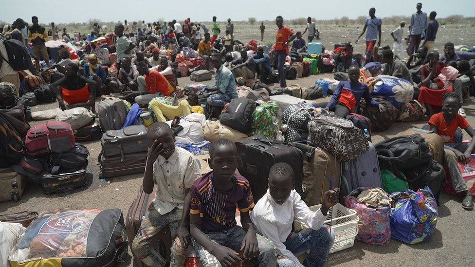 اشتباكات السودان: لاجئون إريتريون عالقون بين أزمتين 2 أشخاص على المدرج مع حقائب سفر في مطار بالويش في جنوب السودان