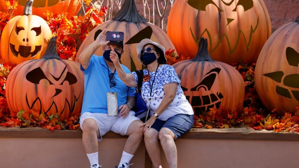 Couple in California wearing face masks taking a selfie in front of giant pumpkins