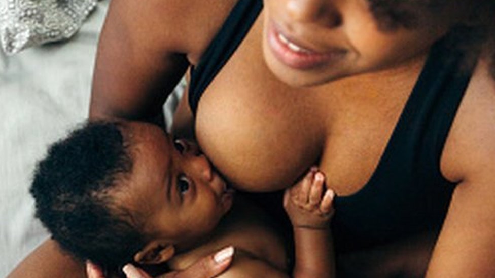 A photo of a baby looking up at mother while being breastfed