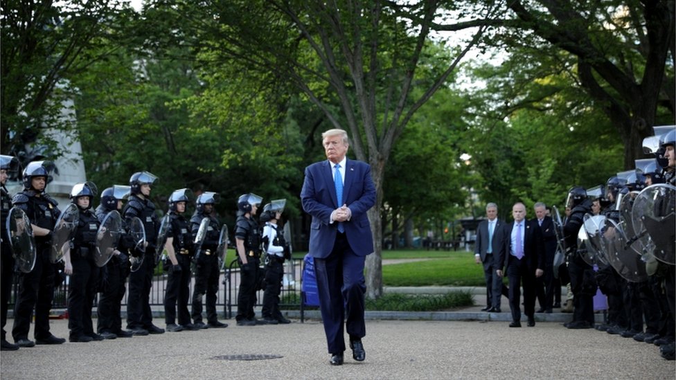 В понедельник президент США Дональд Трамп проходит между линиями полиции по охране общественного порядка