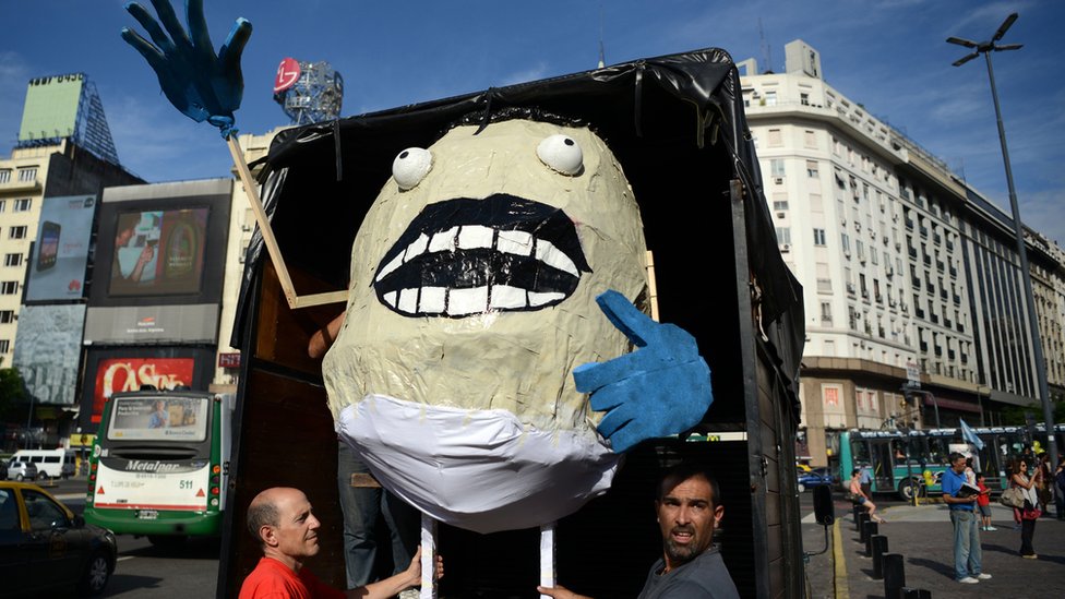 Мужчины несут гигантский манекен ньокки во время демонстрации против массового увольнения государственных служащих в центре Буэнос-Айреса, 29 января 2016 г.