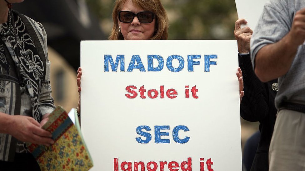 Manifestante com cartaz em que se lê: Madoff roubou, a SEC ignorou