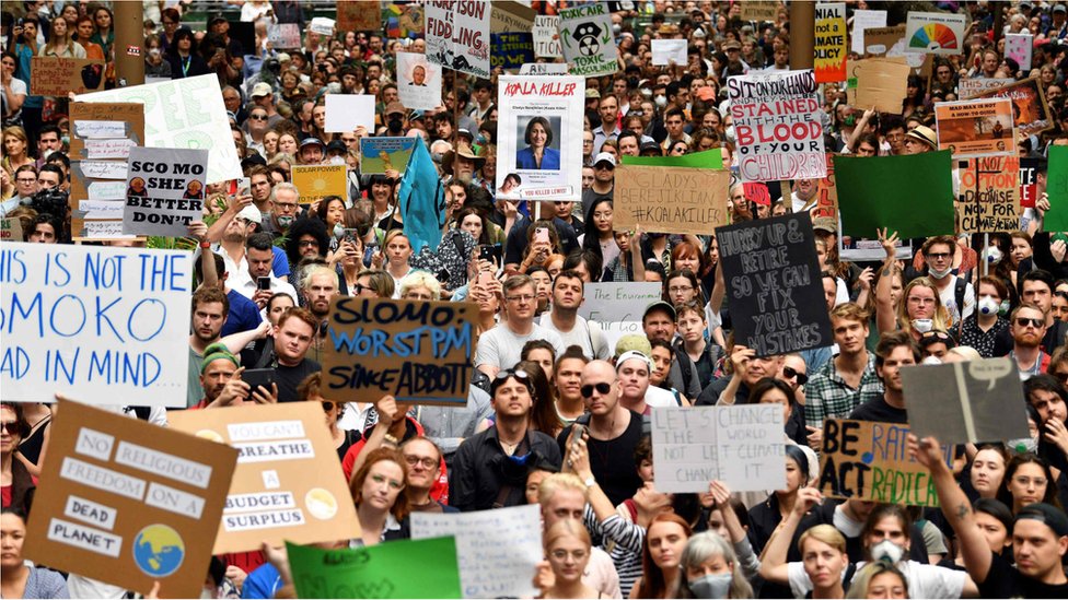 Демонстранты держат плакаты на митинге протеста против изменения климата в Сиднее 11 декабря 2019 г.
