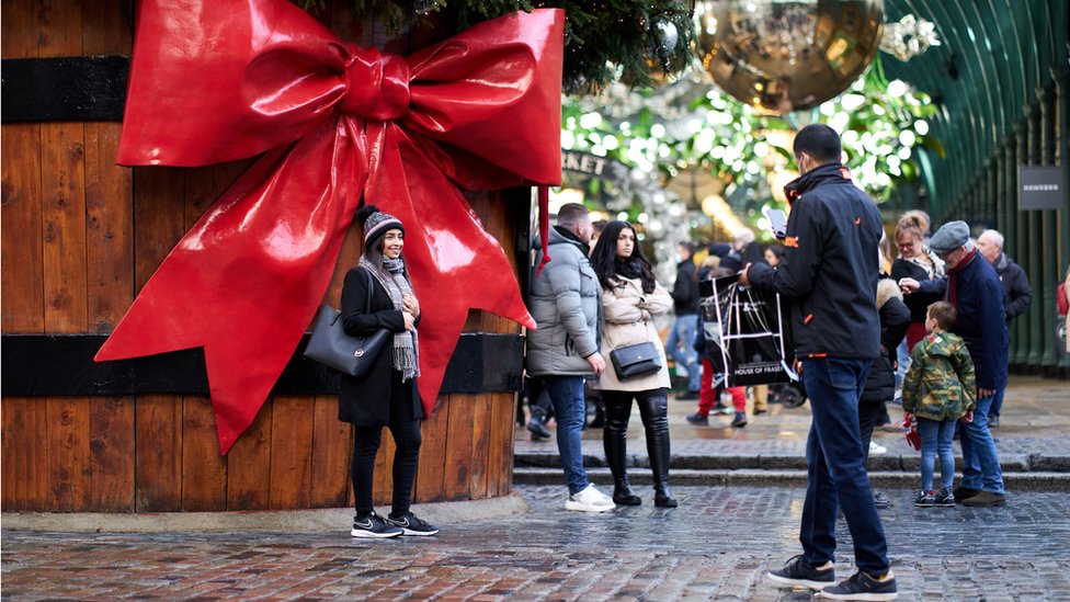 Woman posing next to Christmas decorations in London's Covent Garden