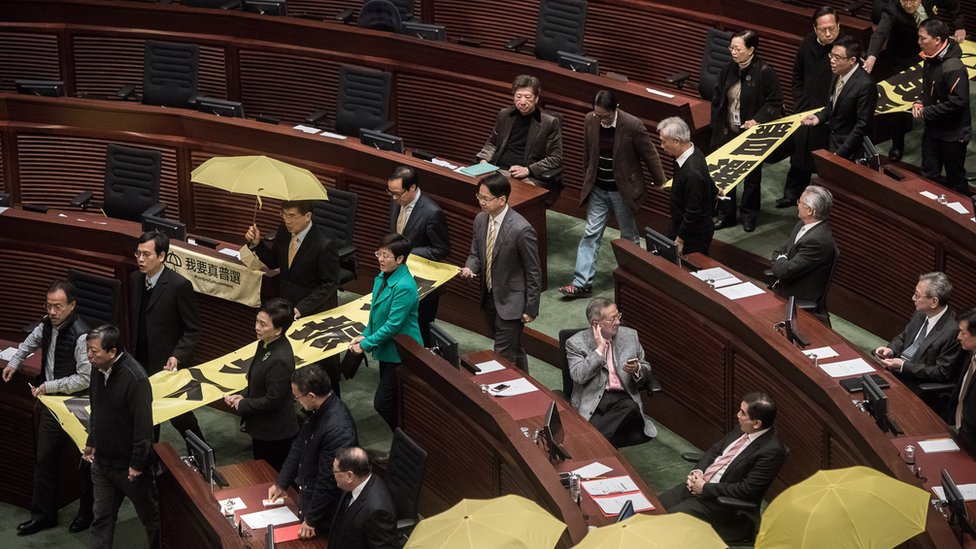 Законодатели, выступающие за демократию, выходят в знак протеста перед политическим обращением главы исполнительной власти Гонконга Люн Чун-ин в законодательном совете Гонконга 14 января 2015 г.