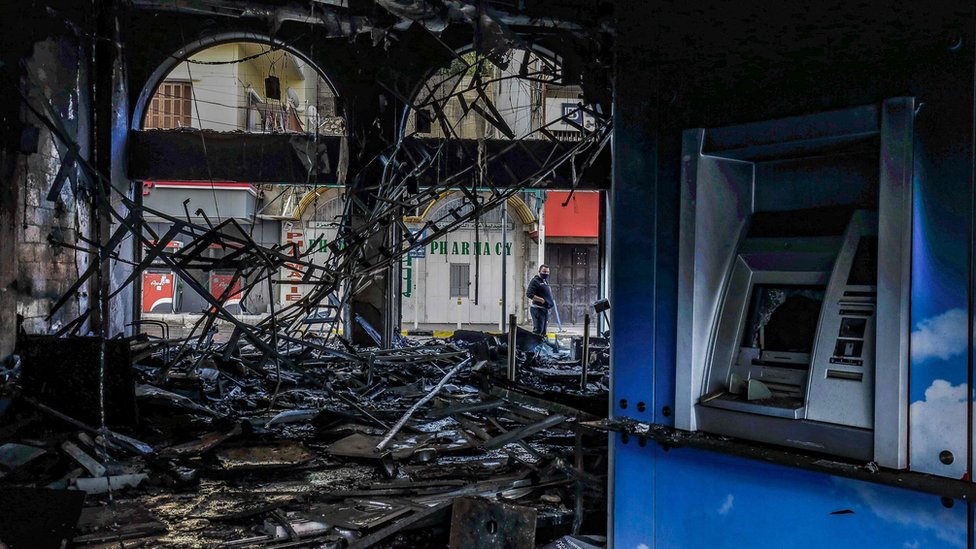 Люди осматривают поврежденный пожаром банк в ливанском городе Триполи 28 апреля 2020 года