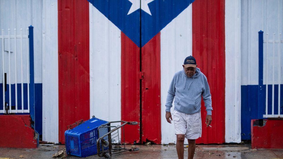 Imagen de un hombre frente a la bandera de Puerto Rico.