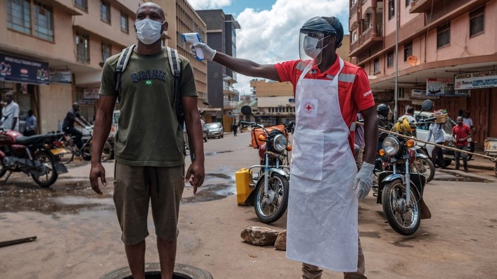 A Red Cross volunteer measures the temperature of a man before he can enter Nakasero market in Kampala, on April 1, 2020