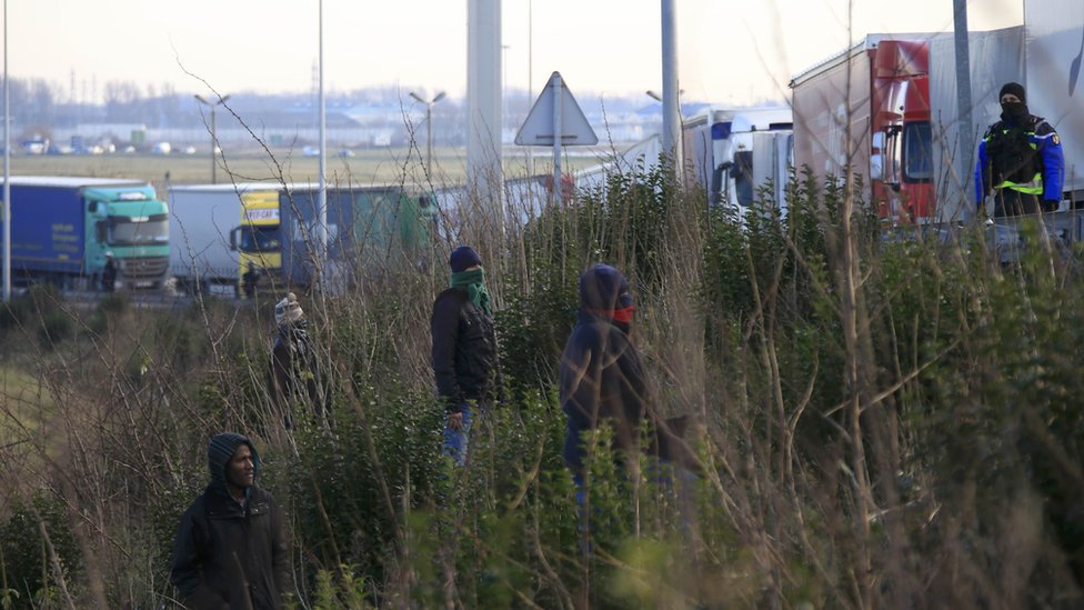 Мигранты на обочине дороги у шеренги грузовиков возле Кале