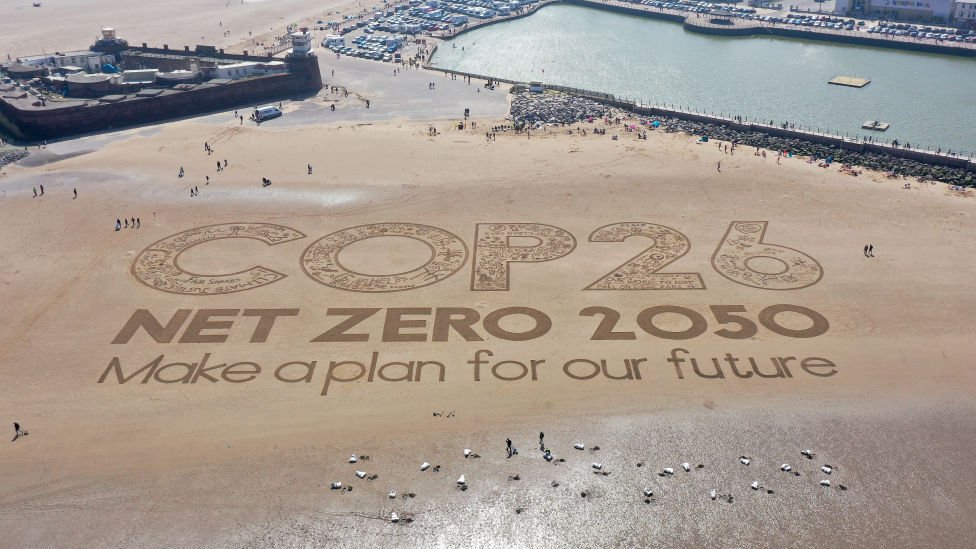 COP26 escrito en la arena en una playa británica.