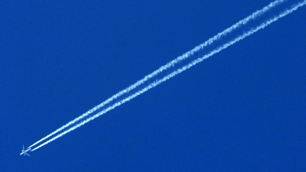 An airplane trailed by a contrail