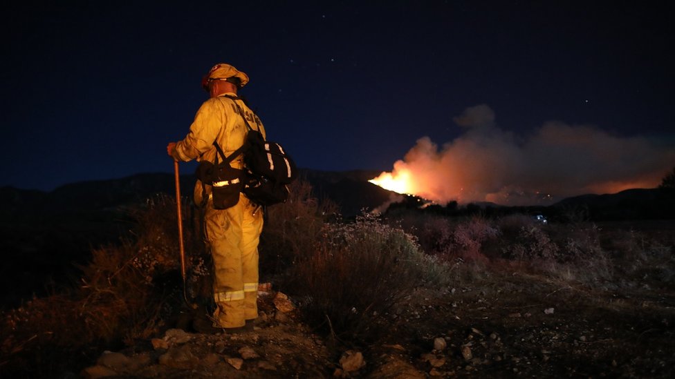 Пожарный сражается с «Яблочным огнем» возле Бомонта в округе Риверсайд, Калифорния