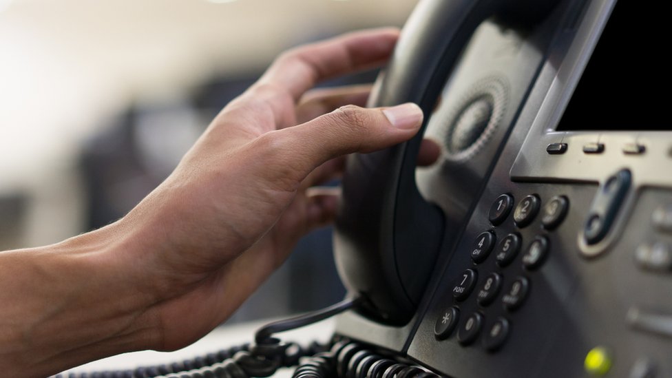Mão segurando telefone usado em telemarketing