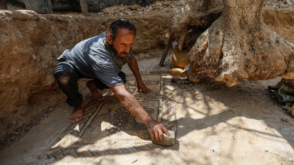 Salman al-Nabahin limpando o piso de mosaico descoberto em sua terra em Gaza