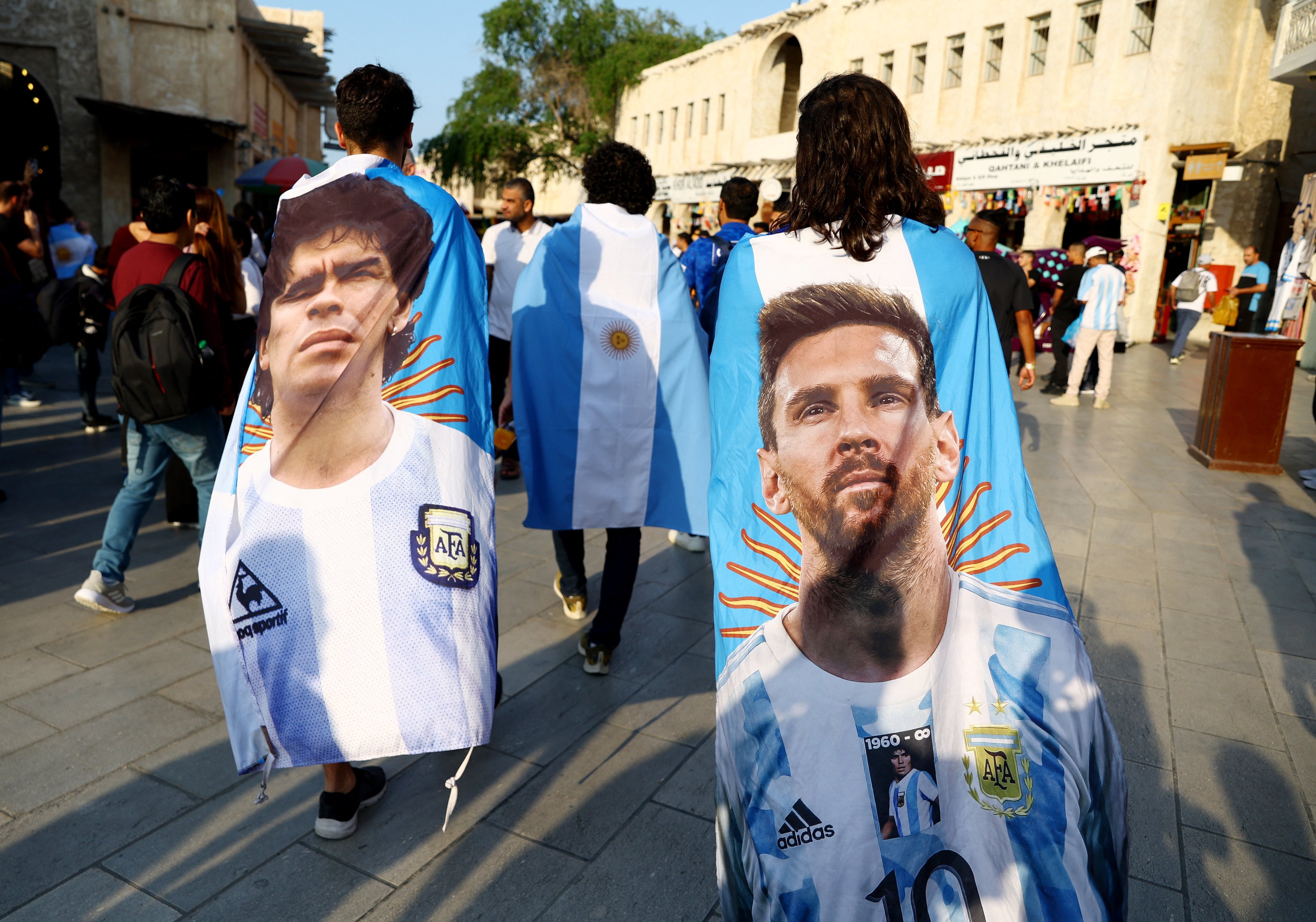 مشجعو الأرجنتين مع علمين عليهما ليونيل ميسي ودييغو مارادونا قبل مباراة نصف النهائي الأرجنتين ضد كرواتيا. سوق واقف، الدوحة، قطر