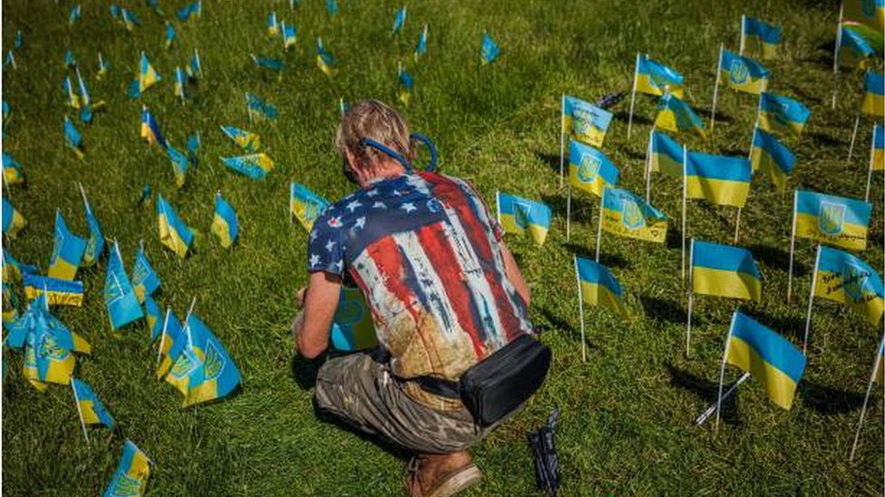 شاب يزرع أعلاماً اوكرانية تحمل أسماء من قتلوا خلال الغزو الروسي لأوكرانيا.
