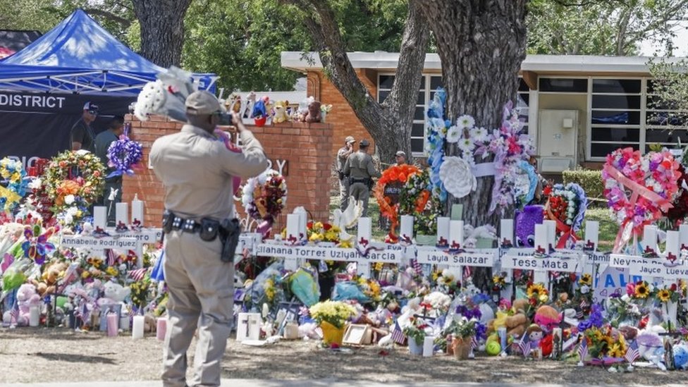 Un agente de Texas toma fotos con un teléfono celular del monumento a las víctimas luego del tiroteo masivo en la Escuela Primaria Robb en Uvalde, Texas.