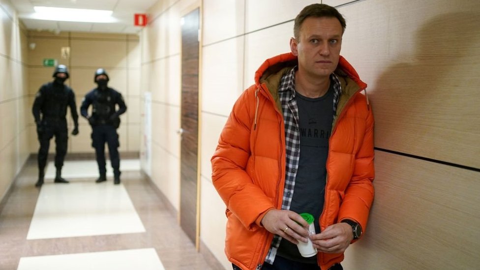 Russian opposition leader Alexei Navalny stands near law enforcement agents in a hallway of a business centre, which houses the office of his Anti-Corruption Foundation (FBK), in Moscow on December 26, 2019