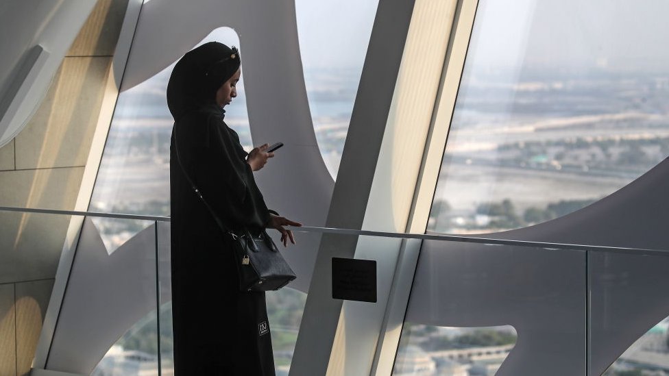Una mujer mira su celular en la ciudad de Dubai en Emiratos Árabes Unidos