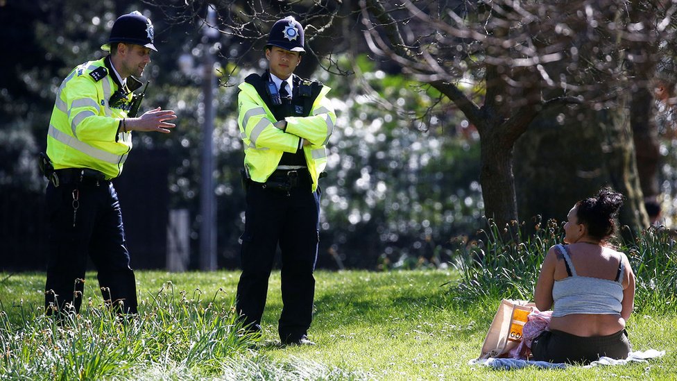 Полиция разговаривает с женщиной, загорающей в парке