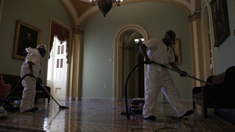 A cleaning crew vacuums the floor of a hallway at the US Capitol 7 January