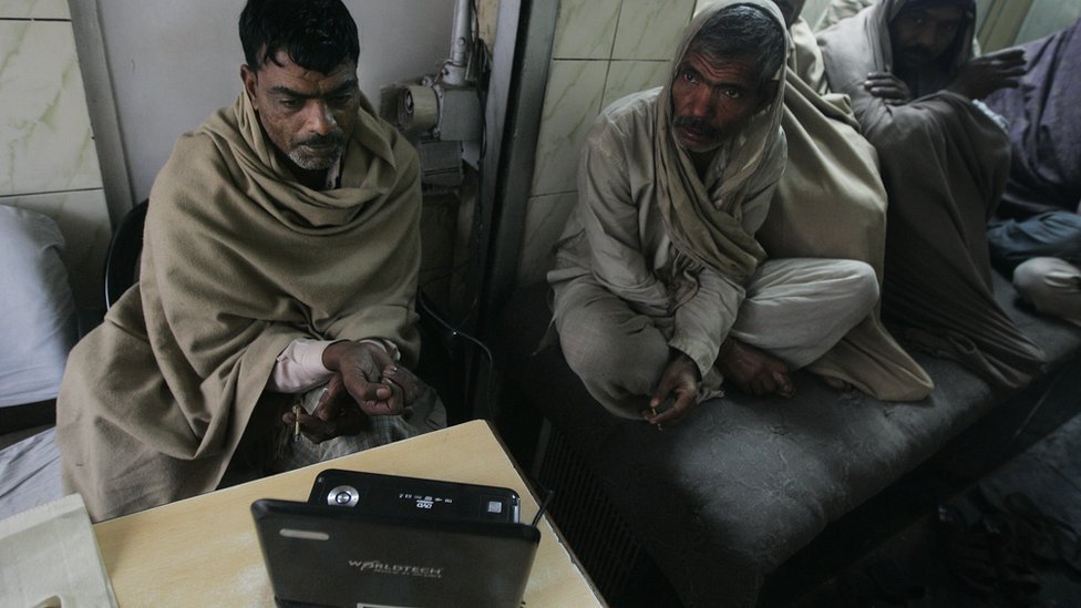 Двое индийских рабочих следят за новостями на портативном компьютере