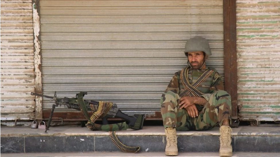 Солдат Афганской национальной армии (АНА) сидит перед закрытым магазином в центре города Кундуз, Афганистан, 3 октября 2016 года.
