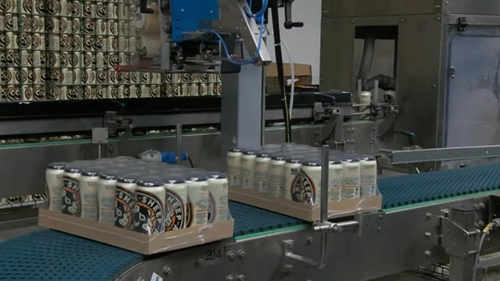Пачки пивных банок на конвейерной ленте производственной линии